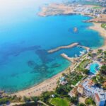 Cyprus landscape. Aerial panoramic view of bay with sandy beach and hotel on coastline, drone photo. Mediterranean vacation and travel concept