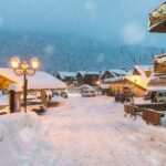 Alpine village under the snow. Macugnaga at dusk, Italy, an important winter and summer tourist resort at the foot of Monte Rosa, Main square in the center of the village during the Christmas period
