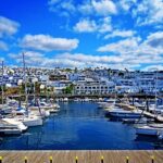 Lanzarote Puerto del Carmen harbour and marina against blue sky white cloud and palm trees